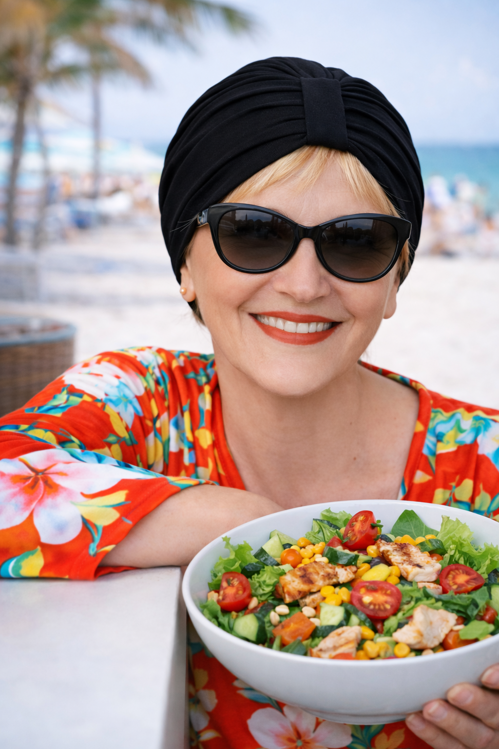 Frau mit schwarzem Turban und Sonnenbrille sitzt im Strandcafé