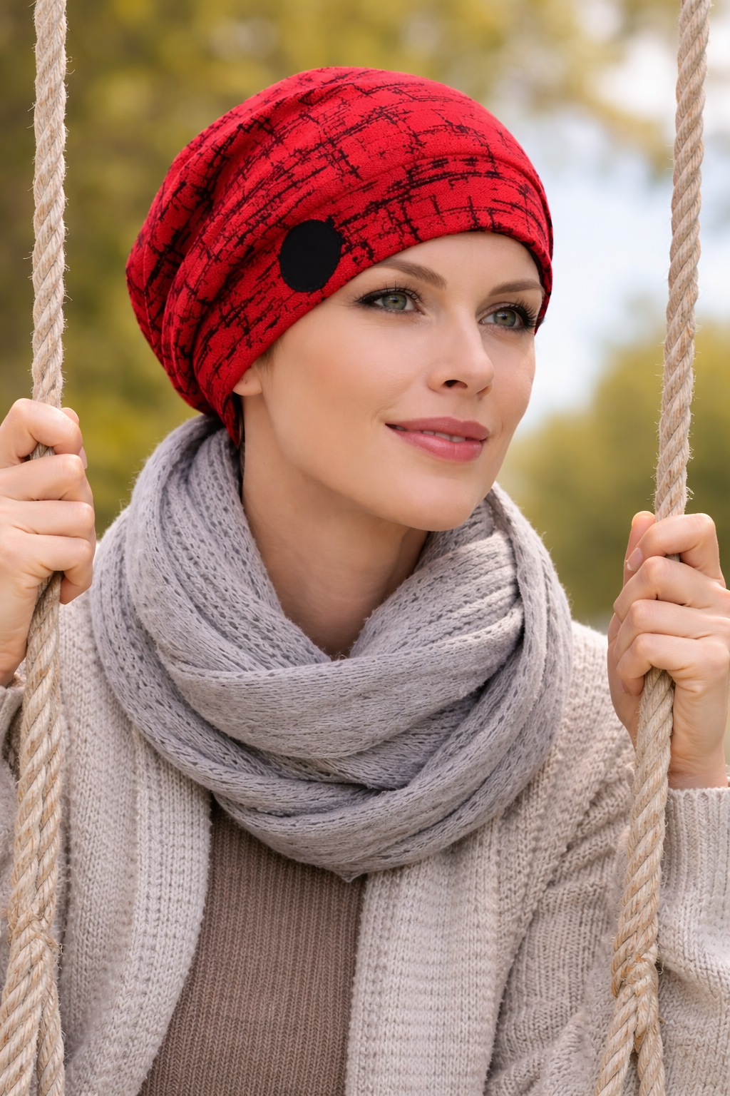 Frau mit Turbanmütze sitzt auf einer Schaukel im Freien