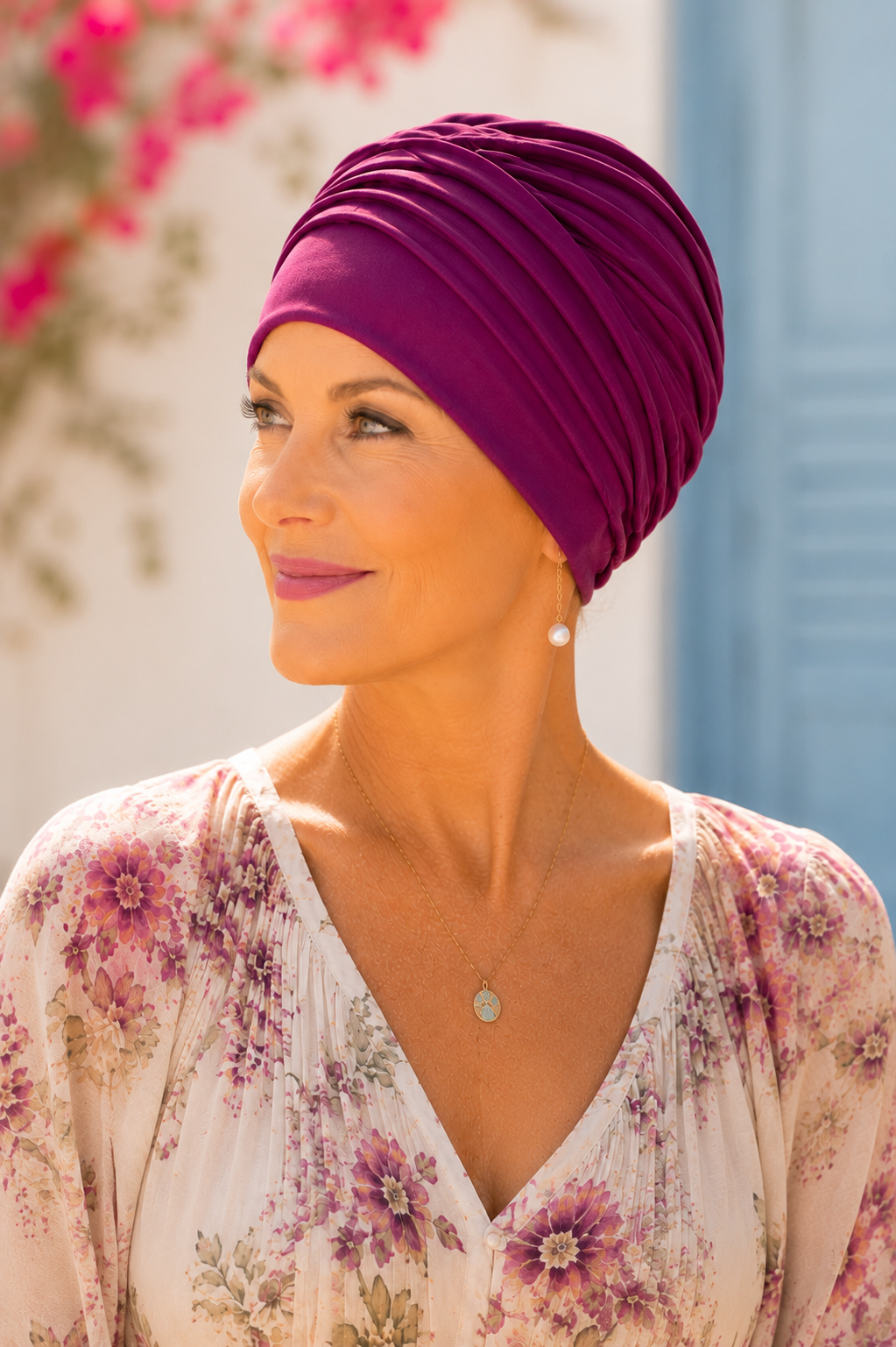 Dame mit beerefarbener Chemomütze und floraler Bluse im Freien.