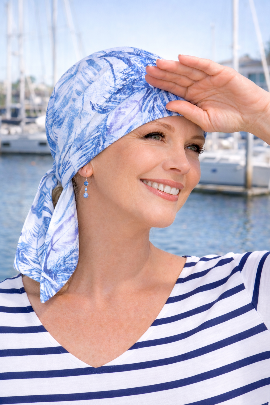 Fertig gebundenes Chemotuch in Blau-Weiß, Frau im Sommer am Hafen – bequeme Kopfbedeckung bei Chemotherapie.