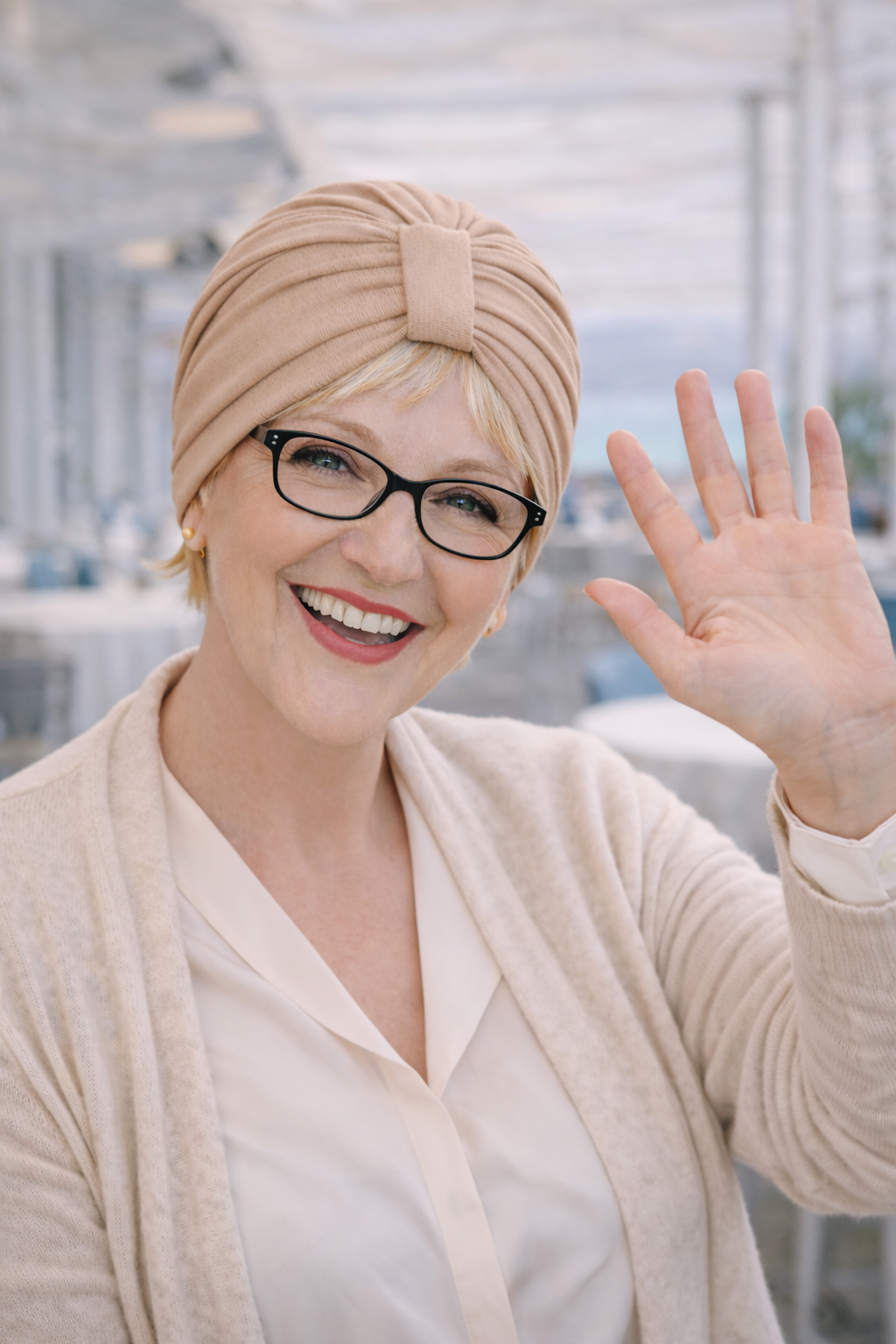 Frau trägt einen beigen Turban und lächelt im Café