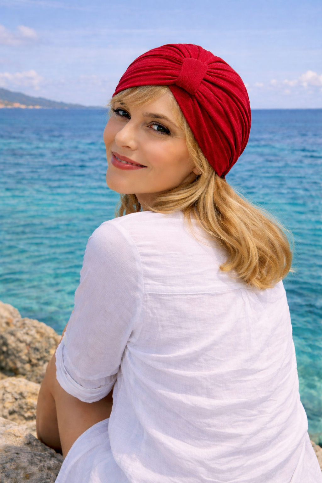 Frau trägt einen roten Turban und sitzt am Meer