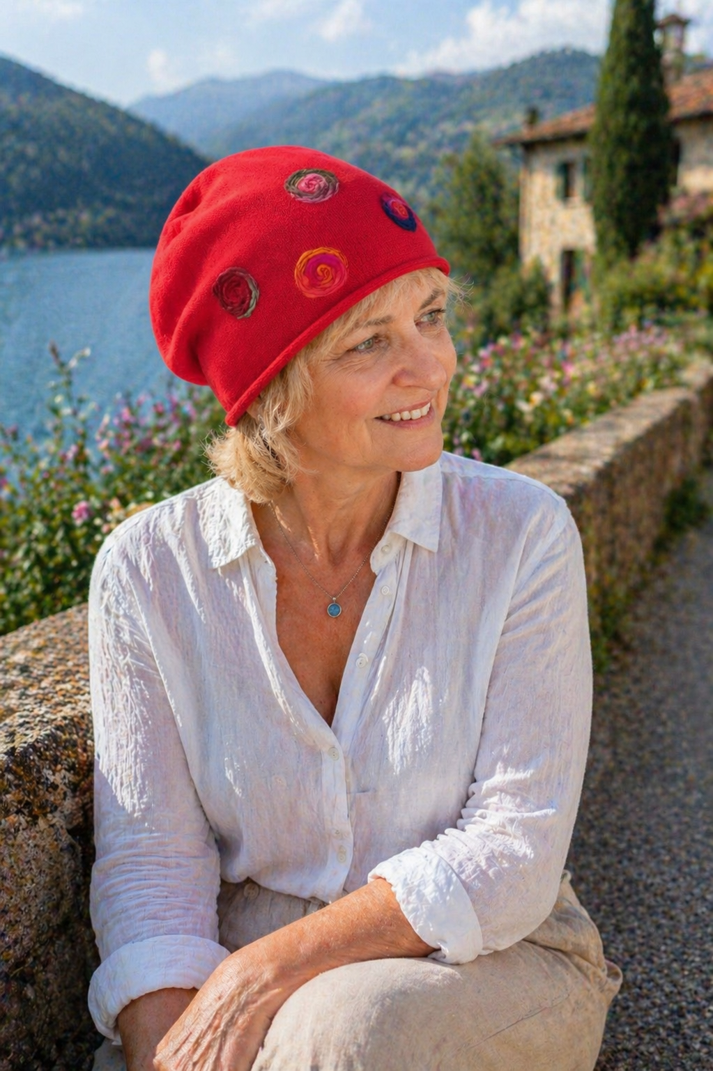 Ältere Frau trägt rote handgemachte Baumwoll Sommermütze und blickt lächelnd über einen See